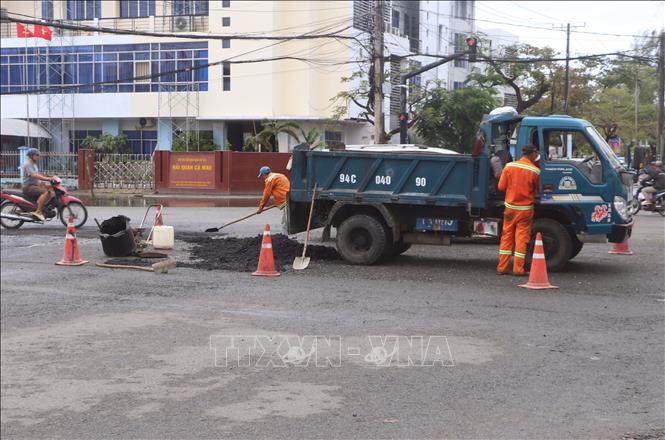 Công nhân thi công thảm nhựa những ổ voi, ổ gà ở tuyến đường phường An Xuyên. Ảnh: Tuấn Phi - TTXVN