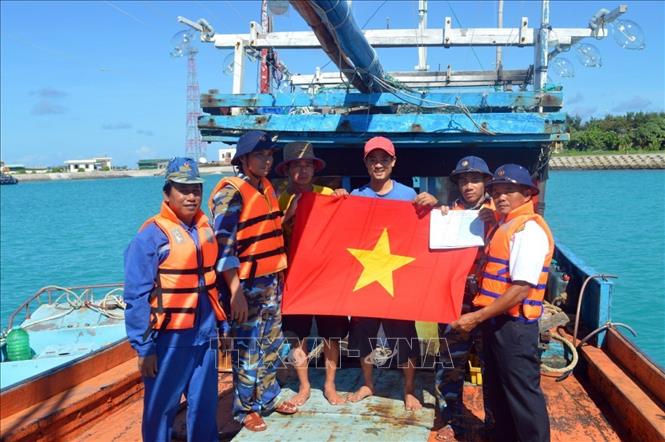 Cán bộ Trung tâm Dịch vụ Hậu cần - Kỹ thuật của Hải đoàn 129 Hải quân tặng cờ Tổ quốc, áo phao cho ngư dân. Ảnh: TTXVN phát 