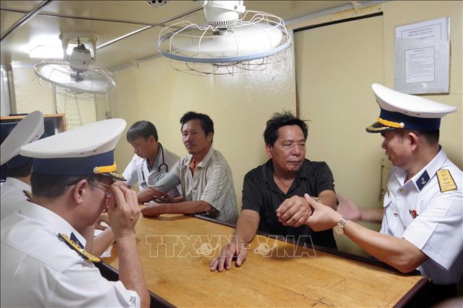 Thượng tá Bùi Ngọc Sang, Chính ủy Hải đoàn 129 Hải quân thăm hỏi ngư dân bị bệnh được tàu của đơn vị đưa từ biển về đất liền cứu chữa. Ảnh: TTXVN phát 