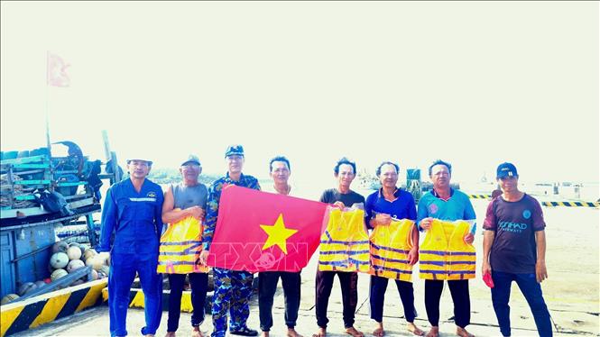 Cán bộ Trung tâm Dịch vụ Hậu cần - Kỹ thuật của Hải đoàn 129 Hải quân tặng cờ Tổ quốc, áo phao cho ngư dân. Ảnh: TTXVN phát 