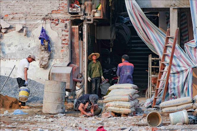 Các thợ xây và máy trộn bê tông hoạt động hết công suất. Ảnh: Vũ Quang – TTXVN