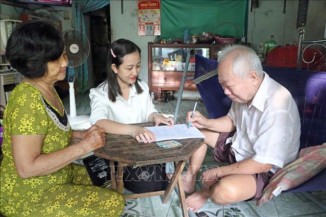 Công chức Trung tâm Phục vụ hành chính công phường Sóc Trăng đến tận nhà người dân để hướng dẫn ký tên vào giấy ủy quyền. Ảnh: Trung Kiên - TTXVN