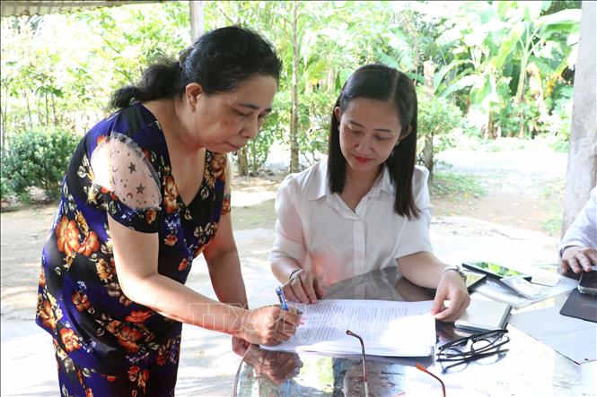 Hộ dân có nhu cầu thực hiện chứng thực chữ ký tại nhà sẽ được giải thích cặn kẽ và hướng dẫn ký các văn bản ủy quyền trợ cấp. Ảnh: Trung Kiên  -TTXVN