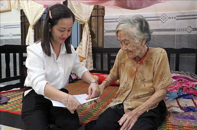 Đối với những trường hợp người cao tuổi sức yếu, không thể cầm bút ký tên, công chức phường tận tình hỗ trợ thực hiện thủ tục điểm chỉ ngay tại giường. Ảnh: Trung Kiên - TTXVN