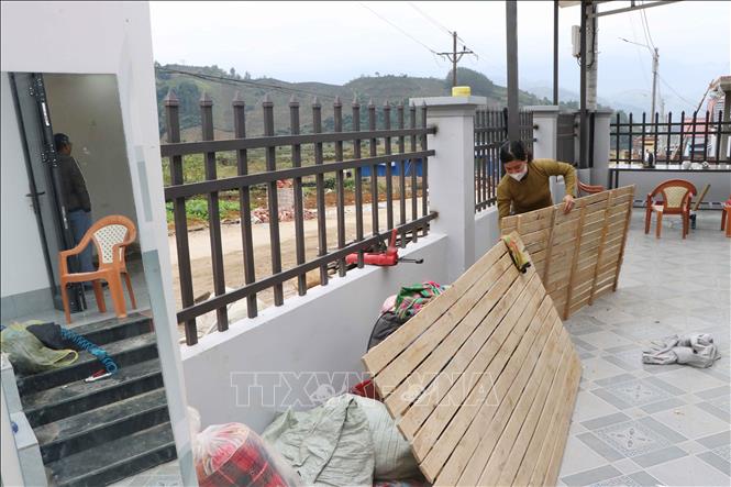 Vợ anh Đèo Văn Tạ, bản Hợp Nhất, xã Bản Bo (Lai Châu) đang dọn vật dụng vào ở ngôi nhà mới xây tại khu tái định cư. Ảnh: Nguyễn Oanh-TTXVN