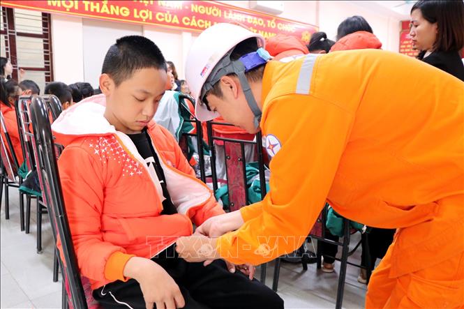 Công nhân Điện lực Hải Phòng giúp trẻ em ở Trung tâm bảo trợ xã hội Hải Dương mặc áo mới. Ảnh: Mạnh Tú - TTXVN