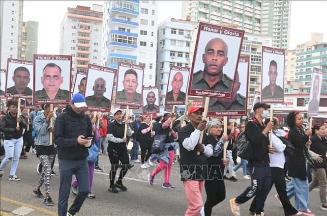 Người dân với chân dung của các chiến sỹ hy sinh. Ảnh: Việt Hùng-P/v TTXVN tại Cuba