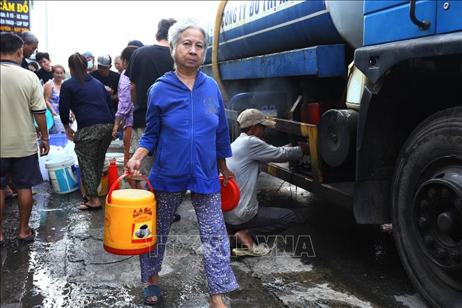 Một bà cụ ở xã Đại Phước, tỉnh Đồng Nai lấy được thùng nước tại điểm tiếp nước về sinh hoạt. Ảnh: Lê Xuân-TTXVN