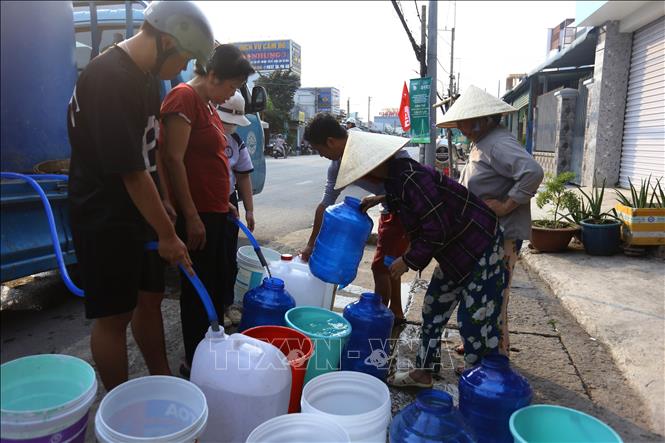 Các hộ dân sống dọc tuyến đường ĐT 769 và khu dân cư thuộc xã Đại Phước, tỉnh Đồng Nai phải mang xô, chậu ra đường chờ các xe chở nước tới lấy nước về sinh hoạt. Ảnh: Lê Xuân-TTXVN