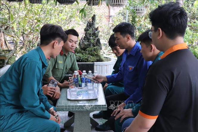 Anh Nguyễn Anh Vũ, Bí thư Đoàn xã Mỹ Lộc hướng dẫn đoàn viên Chi đoàn Công an và Quân sự thao tác mã QR. Ảnh: Thanh Bình -TTXVN