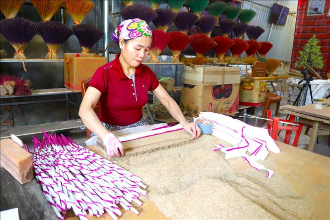 Công đoạn cán hương (xoe hương, quấn hương), lượng rễ hương, vỏ quế, hồi, thảo quả, đinh hương, trầm, bã mía… đã giã nhuyễn thành được định lượng bằng một vỏ nứa có chiều dài tương đương phần lõi của cây hương. Ảnh: Xuân Tiến - TTXVN 