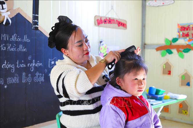 Cô giáo Nguyễn Thị Trâm, giáo viên cắm bản tại điểm trường Mầm non Huồi Măn đang chải tóc cho học trò trước lúc vào lớp. Ảnh: Xuân Tiến - TTXVN 
