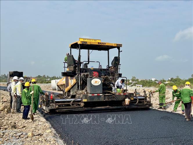 Nhà thầu huy động máy móc, nhân lực trải nhựa hai đường dẫn từ Quốc lộ 91 vào điểm đầu tuyến cao tốc Châu Đốc – Cần Thơ – Sóc Trăng. Ảnh: Thanh Sang-TTXVN