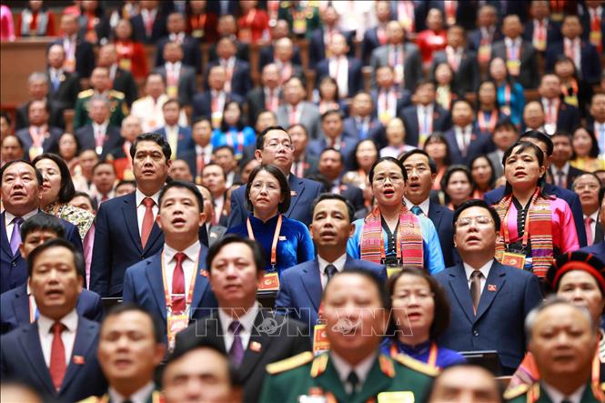 Các đại biểu dự phiên khai mạc Đại hội XIV của Đảng thực hiện nghi lễ chào cờ. Ảnh: TTXVN