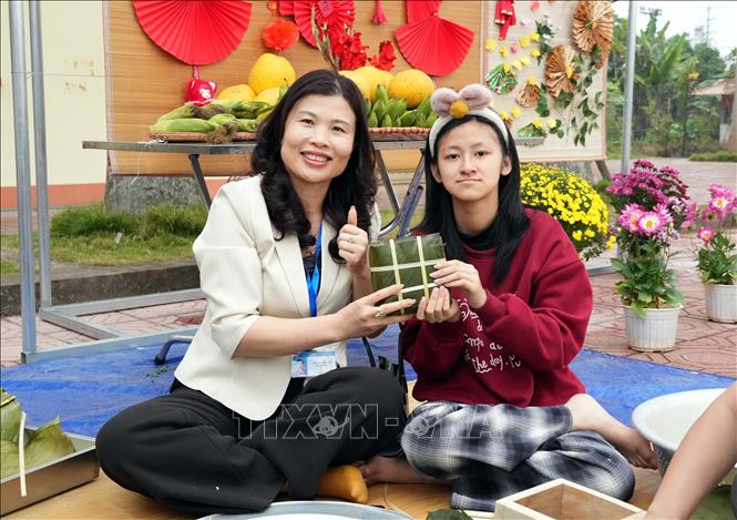 Niềm vui của cán bộ, giáo viên và trẻ khuyết tật khi hoàn thành chiếc bánh chưng trong hoạt động trải nghiệm tại chương trình. Ảnh: Đồng Thúy-TTXVN