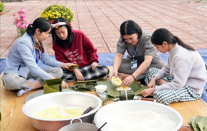 Cán bộ, giáo viên Cơ sở Bảo trợ xã hội tổng hợp Bắc Ninh tận tình hướng dẫn trẻ khuyết tật gói bánh chưng. Ảnh: Đồng Thúy-TTXVN