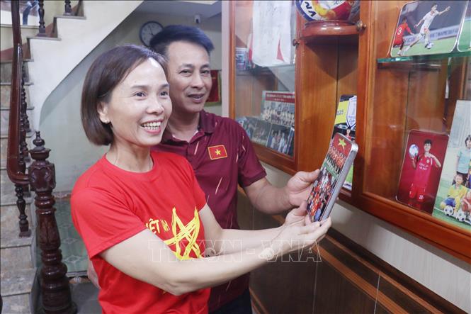 Bố mẹ cầu thủ Phạm Minh Phúc xem lại những bức ảnh lưu niệm của cầu thủ này. Ảnh: Đinh Văn Nhiều-TTXVN