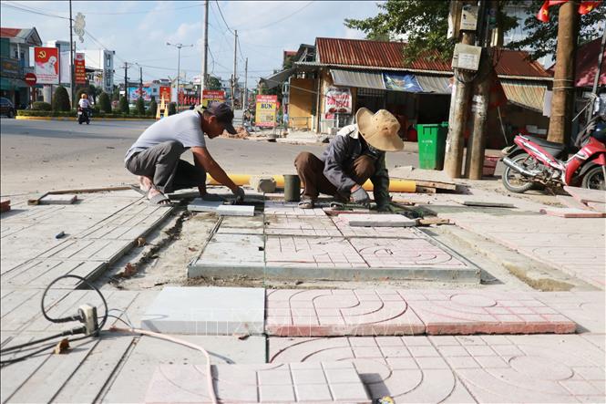 Công nhân lát gạch vỉa hè. Ảnh: Tường Vi - TTXVN