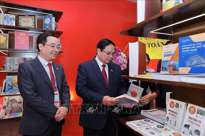 Thủ tướng Phạm Minh Chính xem trưng bày ấn phẩm sách, báo chào mừng Đại hội. Ảnh: TTXVN

