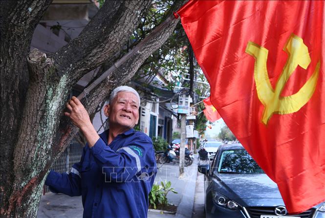 Ông Trần Văn An, Tổ trưởng Tổ dân phố Vị Hoàng 1, phường Nam Định, chỉnh ngay ngắn lá cờ Đảng. Ảnh: Công Luật - TTXVN
