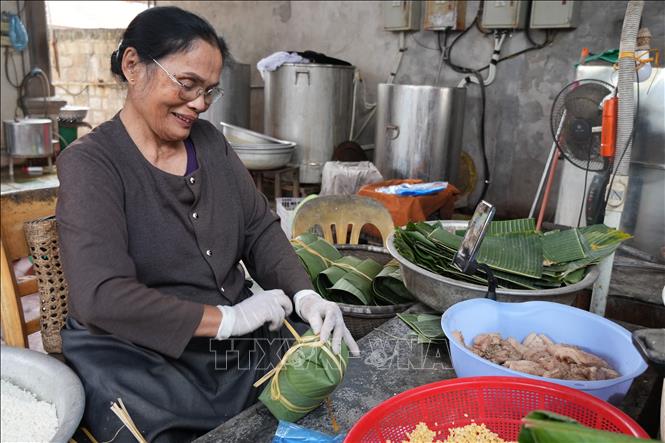 Bà Phạm Thị Thơi, làng Thủy Đường, khẩn trương gói bánh chưng để giao cho khách hàng. Ảnh: Tiến Vĩnh –TTXVN