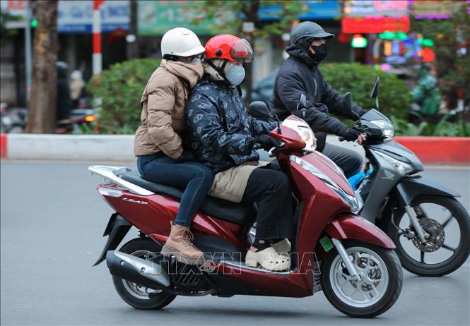Người dân mặc áo ấm, khẩu trang, khăn quàng cổ, găng tay khi phải di chuyển ngoài trời. Ảnh: Hoàng Hiếu - TTXVN