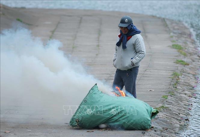 Một người dân đốt lửa tại khu vực hồ Thuyền Quang chiều 22/1. Ảnh: Hoàng Hiếu - TTXVN