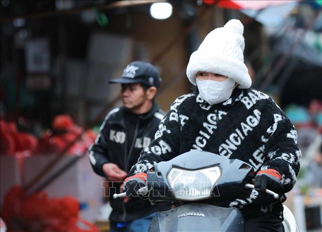 Người dân mặc áo ấm, khẩu trang, khăn quàng cổ, găng tay khi phải di chuyển ngoài trời. Ảnh: Hoàng Hiếu - TTXVN