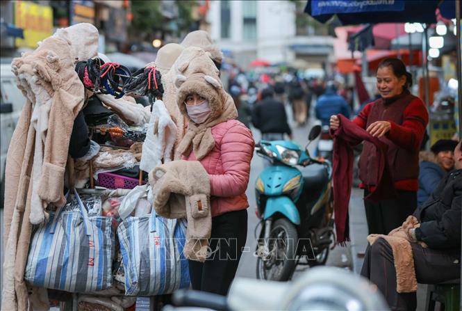 Người lao động, bán hàng trên phố che chắn kỹ chống rét. Ảnh: Hoàng Hiếu - TTXVN