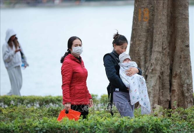 Trẻ nhỏ được che chắn kỹ chống rét khi phải di chuyển ngoài trời. Ảnh: Hoàng Hiếu - TTXVN