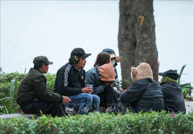 Tại khu vực ven Hồ Gươm, nhiều người dân ngồi co ro khi nhiệt độ giảm sâu nhất từ đầu mùa. Ảnh: Hoàng Hiếu - TTXVN