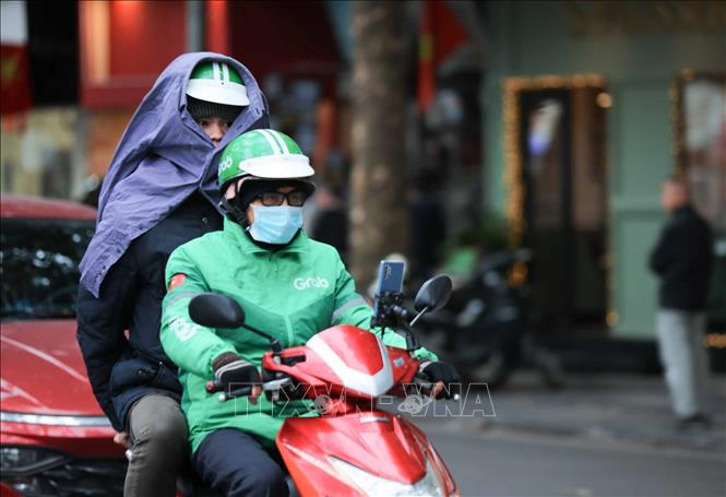 Người dân che chắn chống rét khi phải di chuyển trên đường Hàng Khay. Ảnh: Hoàng Hiếu - TTXVN