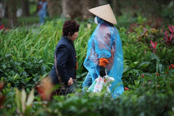 Người lao động ngoài trời ngoài mặc áo ấm còn trang bị thêm áo mưa để che chắn trong đợt rét khắc nghiệt. Ảnh: Hoàng Hiếu - TTXVN 