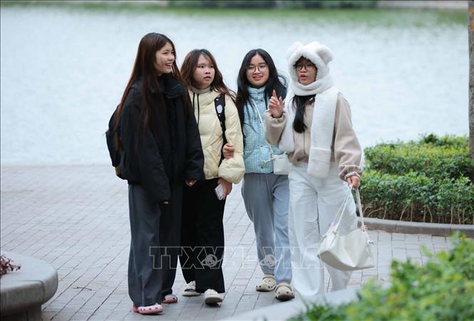 Người dân ra đường đều mặc áo ấm, khăn quàng cổ để đảm bảo sức khoẻ khi phải ra ngoài trời. Ảnh: Hoàng Hiếu - TTXVN