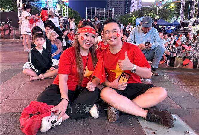 Gia đình anh chị Nguyễn Vương (phường Tân Sơn Nhất) cùng người hâm mộ cổ vũ, tiếp lửa đội tuyển U23 Việt Nam tại phố đi bộ Nguyễn Huệ. Ảnh: Trung Tuyến – TTXVN 
