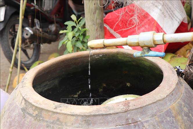 Vòi nước mở cả ngày đêm nhưng hiếm hoi mới có nước chảy vào lu. Ảnh: Thu Hiền - TTXVN