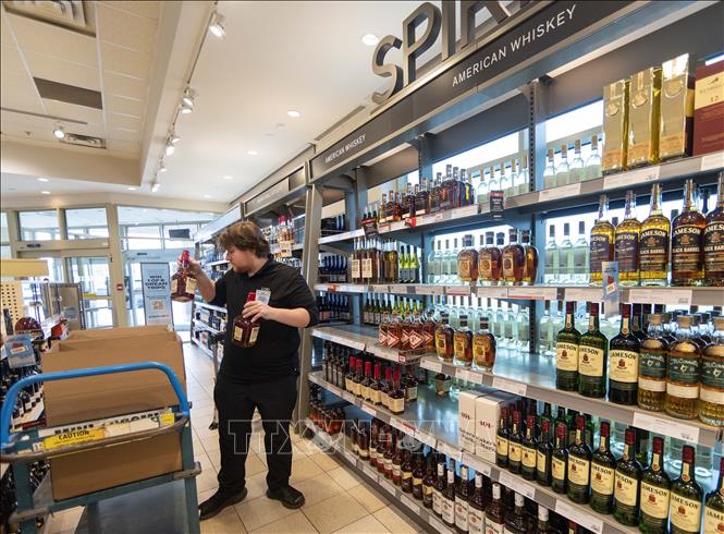 Nhân viên thu hồi những chai rượu sản xuất tại Mỹ trên kệ hàng trong siêu thị ở Oakville, Ontario, Canada. Ảnh: THX/TTXVN 