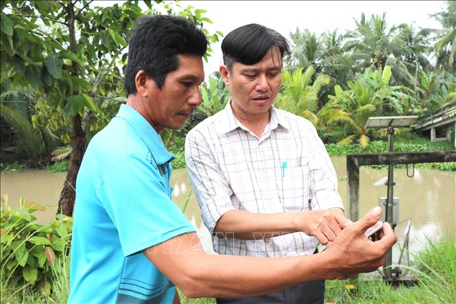 Nông dân theo dõi môi trường nước qua điện thoại thông minh. Ảnh: Thanh Hòa- TTXVN