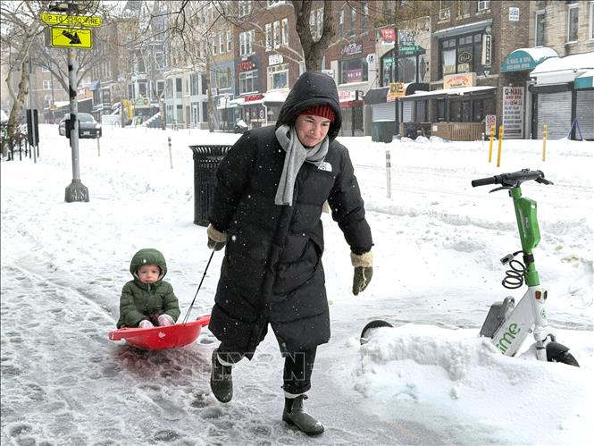 Một phụ nữ kéo con trên ván trượt tại một tuyến phố ở Washington DC ngày 25/1/2026. Ảnh: Ngọc Quang, PV TTXVN tại Mỹ