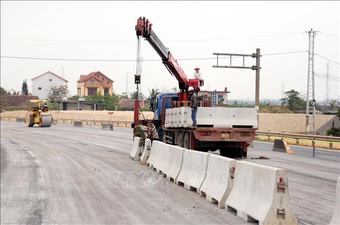 Đơn vị thị công đang hoàn thiện hạng mục dựng giải phân cách cứng ở hai đầu cầu Gianh. Ảnh: Tá Chuyên - TTXVN