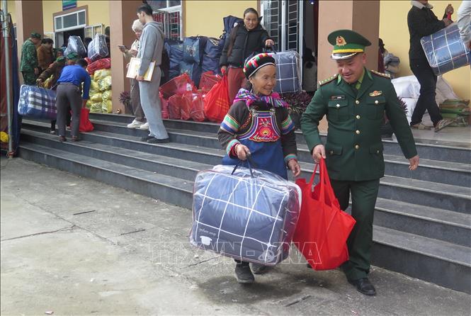 Người dân phấn khởi khi được cán bộ Biên phòng hỗ trợ nhận quà Tết. Ảnh: Hương Thu - TTXVN               