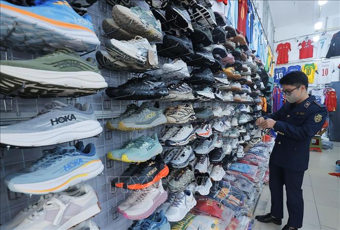 Lực lượng chức năng kiểm tra sản phẩm giầy tại cửa hàng. Ảnh: Trần Việt - TTXVN