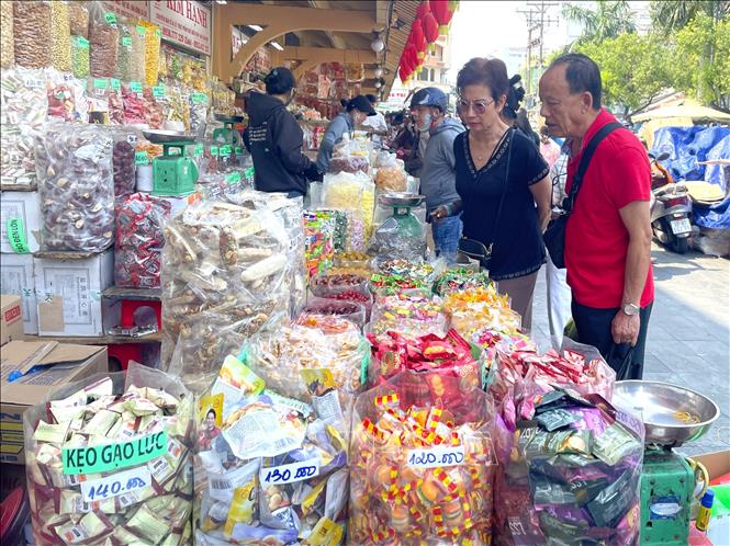 Du khách lựa chọn sản phẩm đặc sản Tết tại chợ Bình Tây, TP. Hồ Chí Minh. Ảnh: Hương Giang - TTXVN