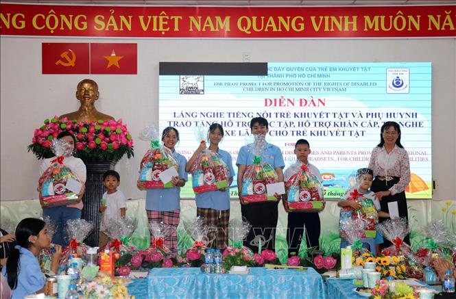 Lãnh đạo Hội Bảo trợ trẻ em Thành phố Hồ Chí Minh trao tặng quà Tết cho trẻ khuyết tật tại diễn đàn. Ảnh: Thanh Vũ-TTXVN
