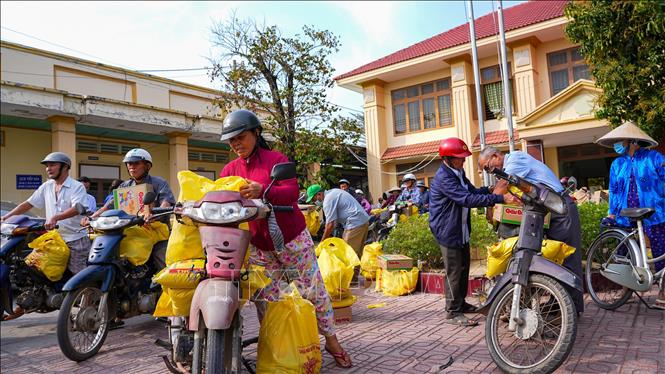 Người dân xã Bến Cầu, tỉnh Tây Ninh phấn khởi nhận gạo và nhu yếu phẩm từ các nhà hảo tâm trong chương trình Tết vì người nghèo. Ảnh: Minh Phú – TTXVN