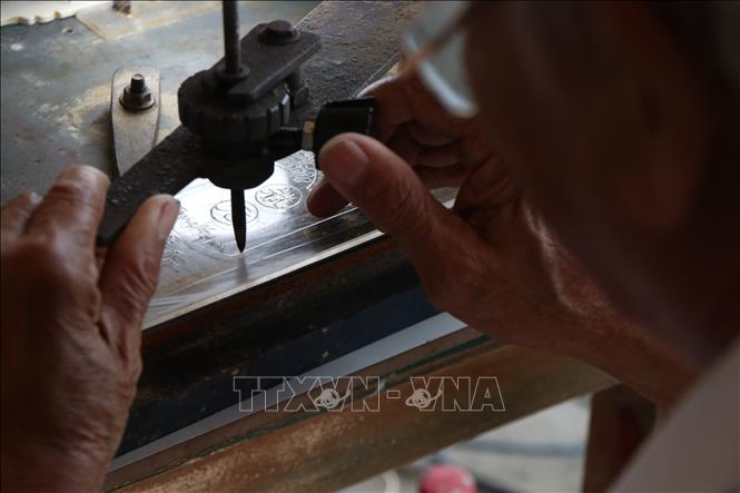 Ông Tố cẩn thận khắc từng chi tiết trên thẻ xăm. Ảnh: Mai Trang - TTXVN 