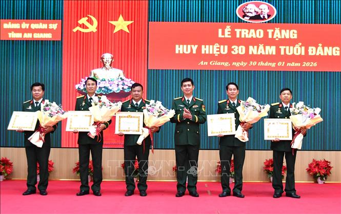 Đại tá Huỳnh Văn Khởi, Phó Bí thư Thường trực Đảng ủy, Chính ủy Bộ CHQS tỉnh An Giang, trao huy hiệu 30 năm tuổi cho 5 đảng viên thuộc Đảng bộ Quân sự tỉnh. Ảnh: Văn Sĩ - TTXVN