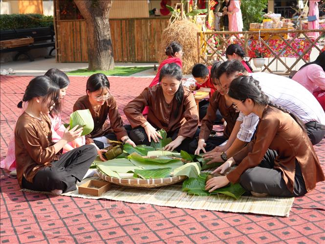 Học sinh Trường THCS Lê Mao trải nghiệm gói bánh chưng. Ảnh: Bích Huệ - TTXVN