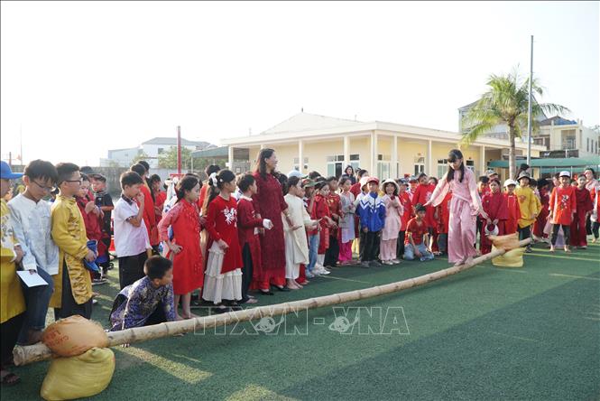 Học sinh trải nghiệm trò chơi dân gian đi cầu kiểu. Ảnh: Bích Huệ - TTXVN                        