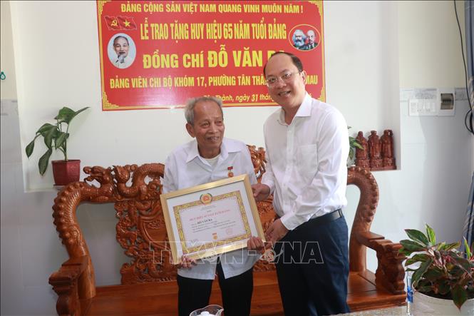 Bí thư Tỉnh ủy Cà Mau Nguyễn Hồ Hải trao Huy hiệu 65 năm tuổi Đảng cho đồng chí Đỗ Văn Ba. Ảnh: Huỳnh Anh - TTXVN
